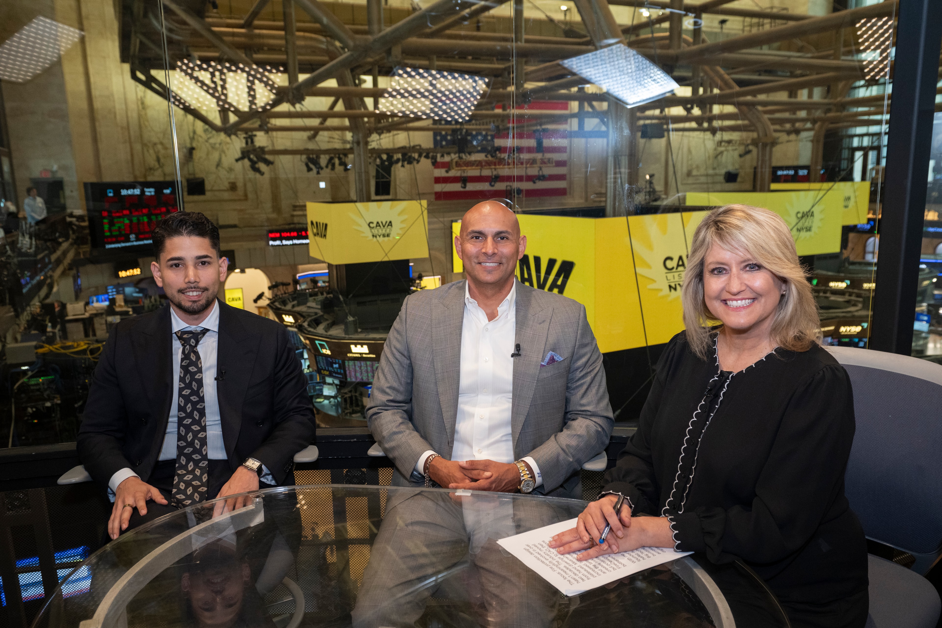 Omar Hafez with a colleague and an interviewer at the broadcast desk on the New York Stock Exchange floor